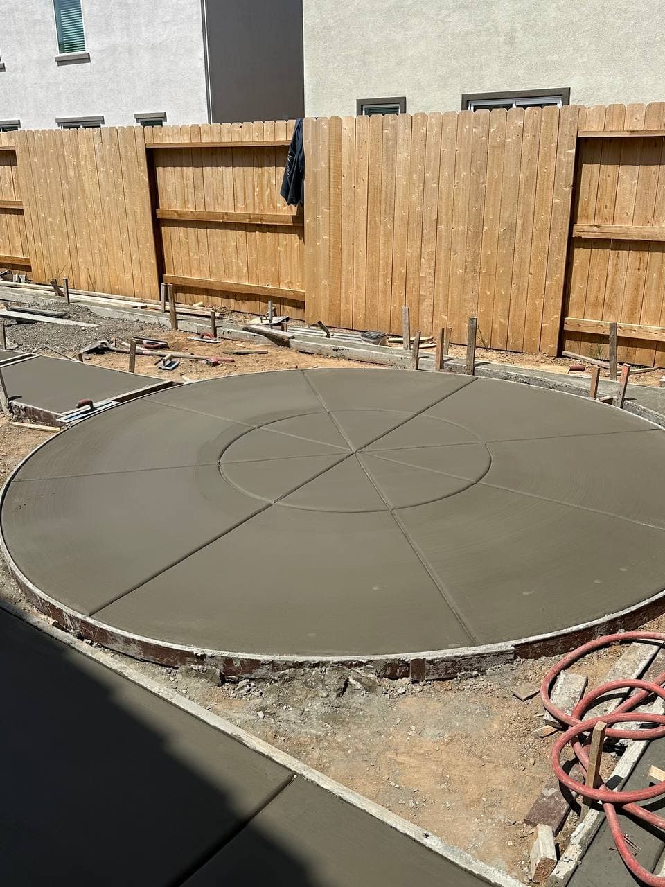Freshly poured circular concrete patio with decorative scoring