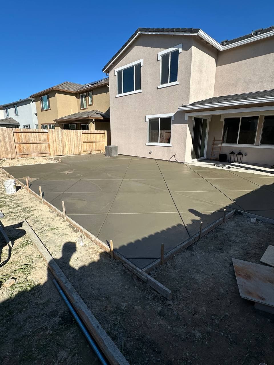 Large freshly finished concrete patio behind a two-story home