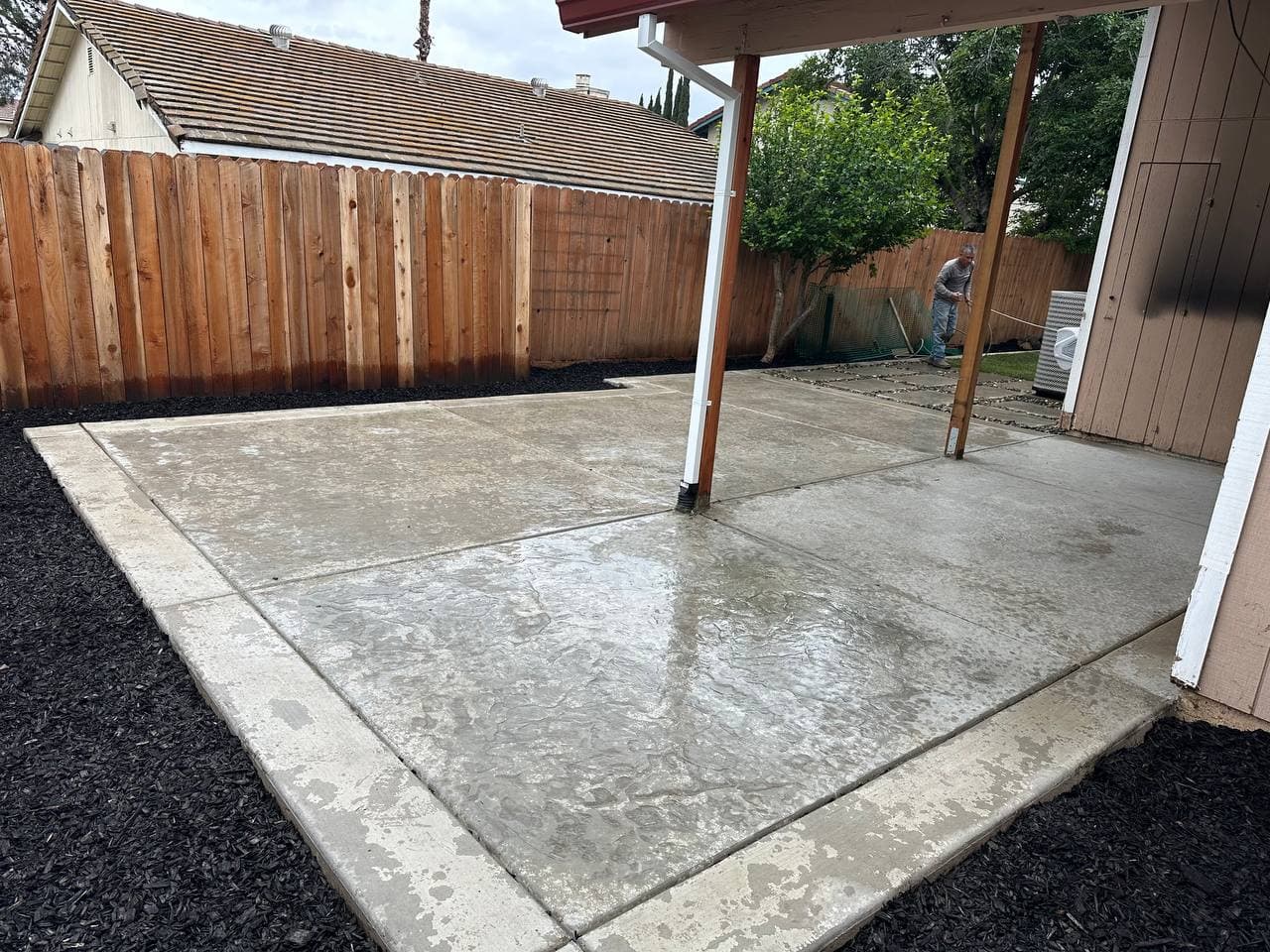 Freshly poured stamped concrete patio in a fenced backyard